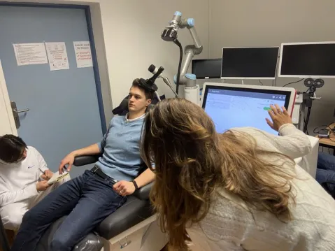 patient sitting in medical stool, two scientists taking notes and checking the screen