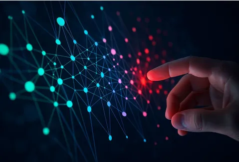 a hand reaching out to a screen showing a network of different colored dots